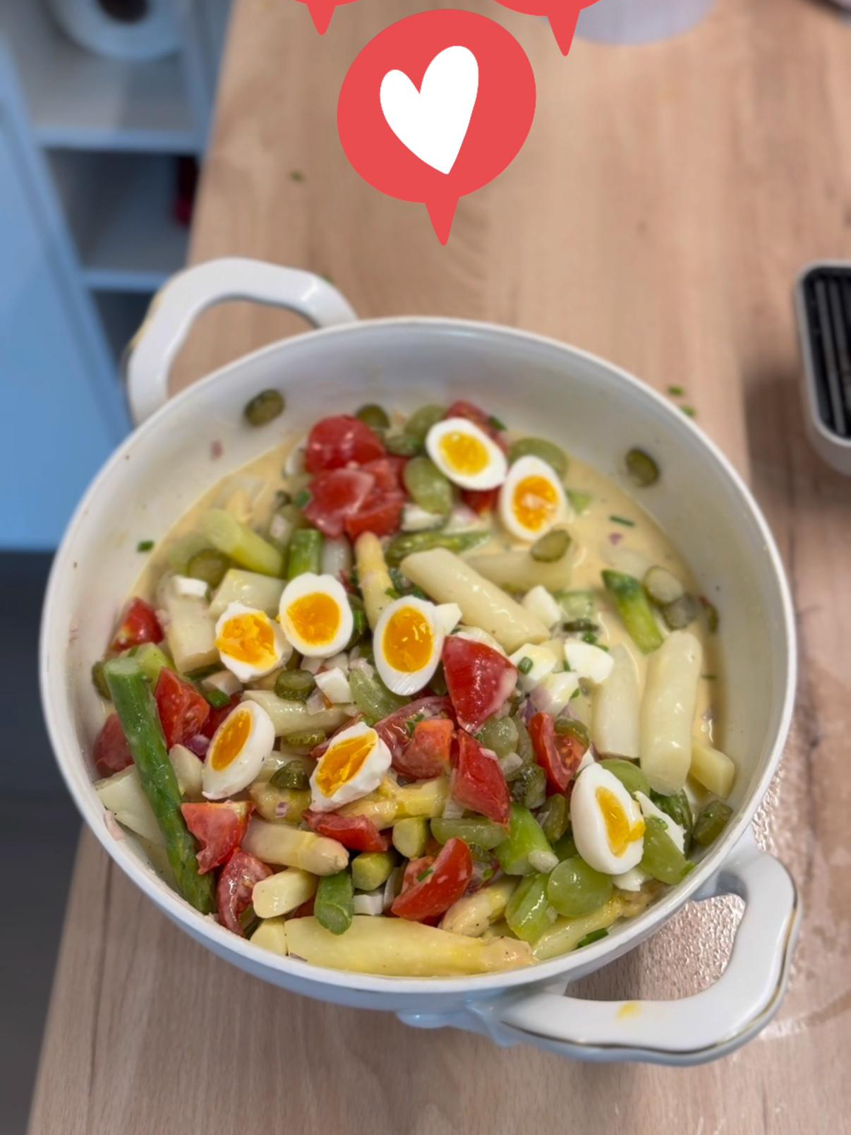 Eine Person in einer Küche hält grün-weißen Spargelsalat