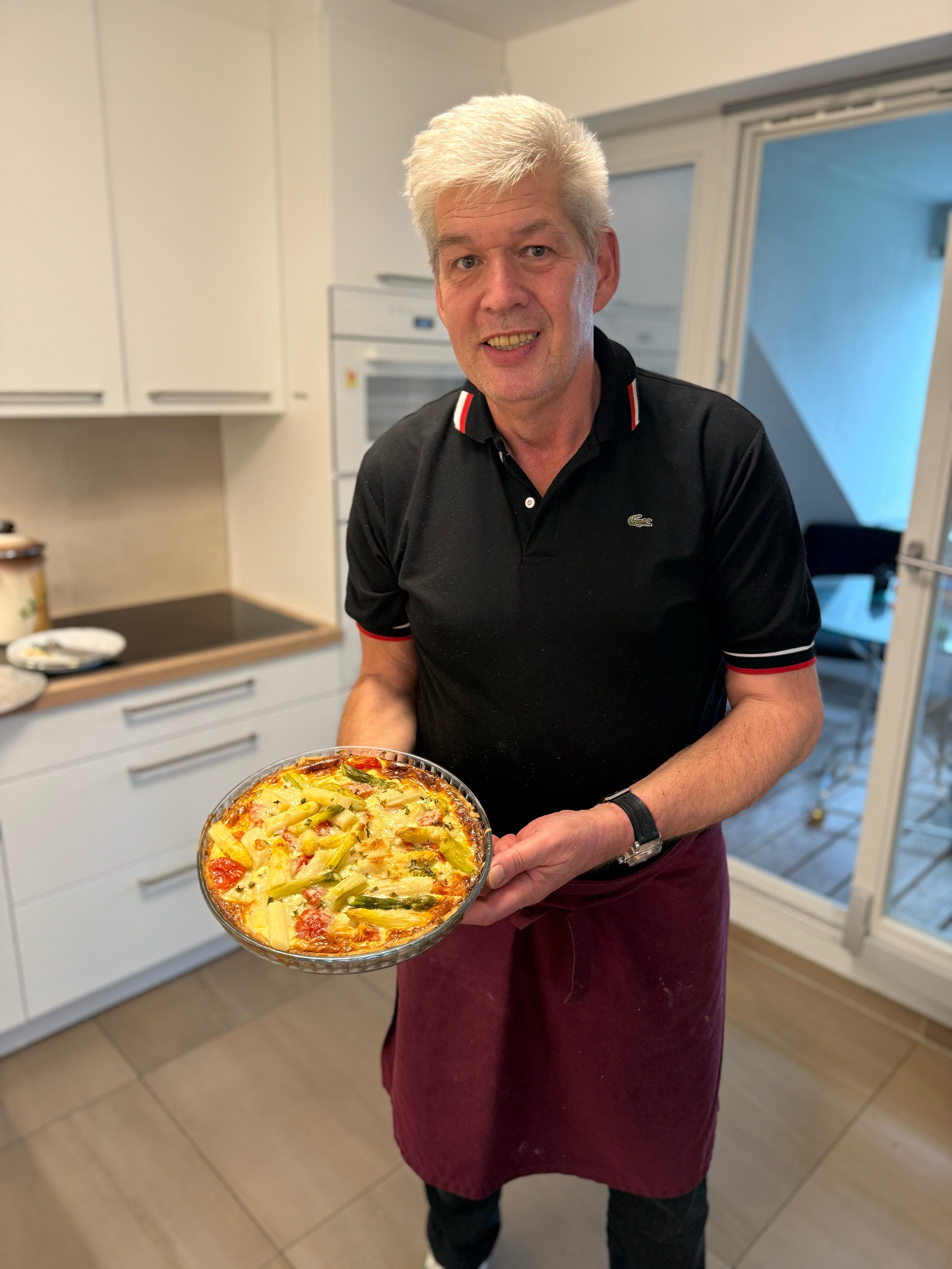 Eine Person in einer Küche hält grüne Spargelquiche